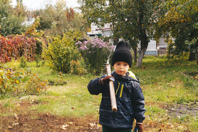 Child helps to clean up the leaves in the backyard garden. 