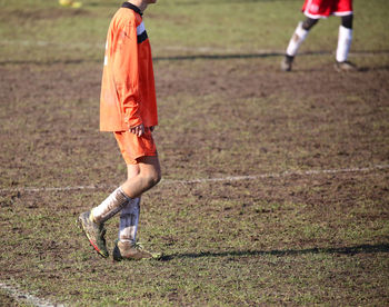 Low section of man playing soccer on field