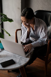 Businesswoman using laptop while sitting on sofa at home