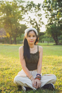Portrait smiling asian woman in a green singlet sitting on a lawn with nature background in a park