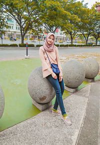 Portrait of smiling young woman outdoors sitting on boulder round