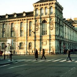 People walking on road against buildings in city