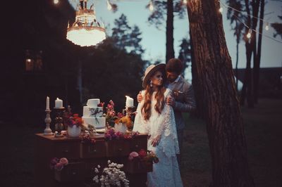 Newlywed couple kissing while standing by cake