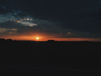 Silhouette landscape against dramatic sky during sunset