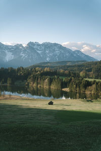 Scenic view of grass field against sky with small mountain cabin