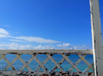 Railing by sea against blue sky