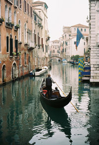 Rear view of gondolier rowing boat in canal