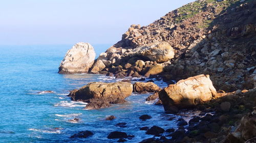 Rocks on sea shore against sky