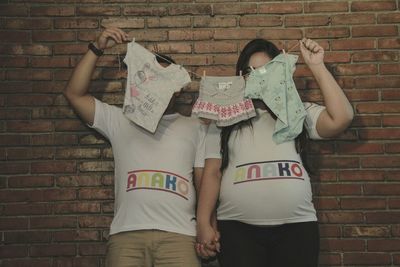 Midsection of couple standing against brick wall