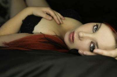 Close-up portrait of seductive woman lying on bed at home