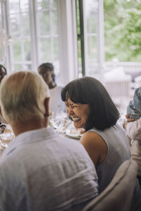 Happy woman looking at man while having dinner at party