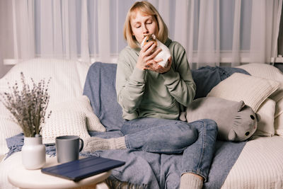 Young woman using phone while sitting on sofa at home