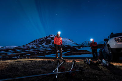 A woman getting ready to ski with mountains and northern lights