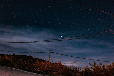 Low angle view of electricity pylon against sky at night