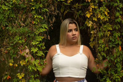 Portrait of young woman standing against plants