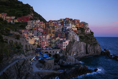 Townscape by sea against sky during sunset