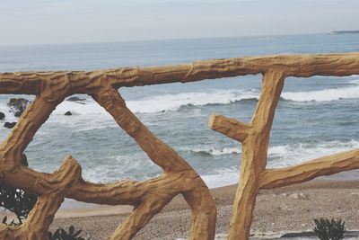 Close-up of wooden post on beach against sky