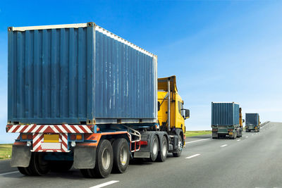 Vehicles on road against blue sky