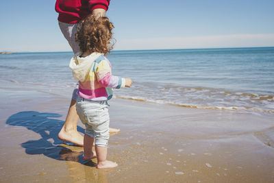 Rear view of girl standing at beach