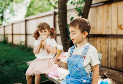 Two young kids sitting outside eating ice cream cone