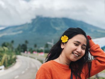 Portrait of smiling young woman standing against sky