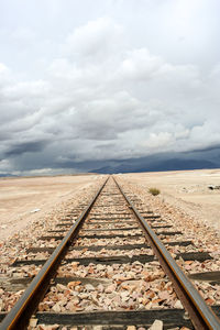Surface level of railway tracks against cloudy sky