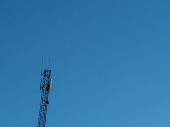 Low angle view of communications tower against clear blue sky