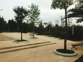 Footpath by swimming pool in park against sky