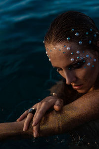 Young woman with golden skin in water portrait