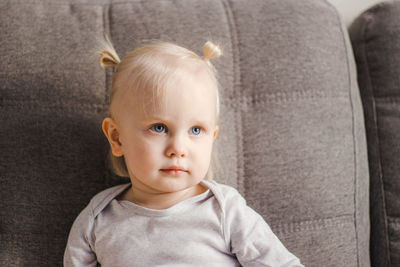 Portrait of cute boy sitting on sofa at home