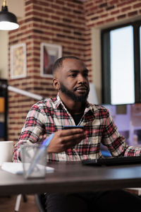 Side view of young man looking away while sitting in office