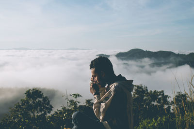 Side view of man looking at sea of mist against sky