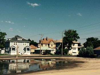 Houses by buildings in town against sky