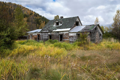 Abandoned house on field against sky