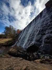 Low angle view of waterfall against sky