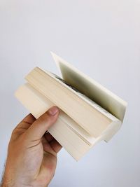 Cropped hand holding book against white background