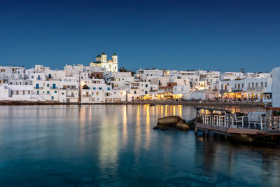 River by buildings against clear blue sky