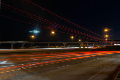 Light trails on road against sky at night