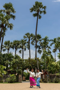 Women standing on land against palm trees and sky