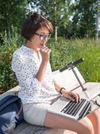 Young woman using mobile phone while sitting at park