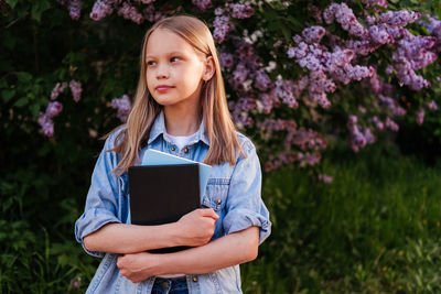 Portrait of young woman standing against plants