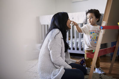 Cute playful son touching mother's nose while drawing on canvas at home