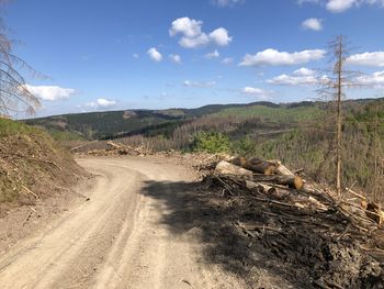 Dirt road by land against sky