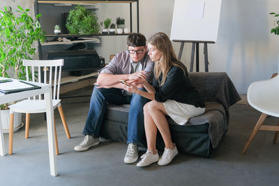 Young woman using laptop while sitting on chair at home