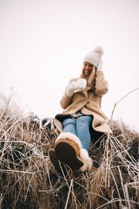 Side view of woman sitting on hay against white background