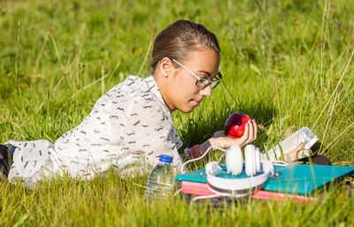 Young woman reading book while lying on grass at park