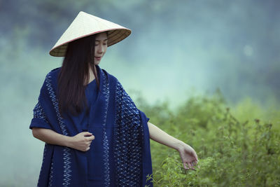 Woman wearing hat standing on field against sky