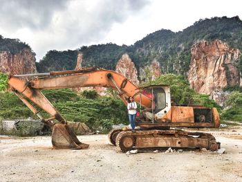 Woman standing on earth mover at construction site against sky