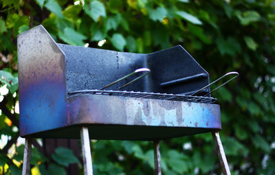 Close-up of barbecue grill against blurred plants