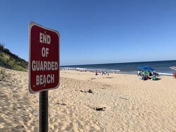 Information sign on beach against clear sky